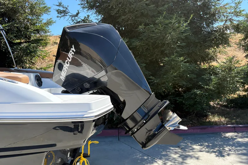 Slide: The Image of 2027 Tahoe 210 S boat with Mercury outboard motor, parked outdoors. - 11