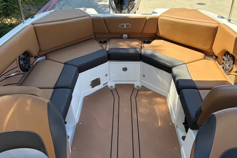 Slide: The Image of 2027 Tahoe 210 S boat interior with tan and black seating, featuring cup holders and speakers. - 21