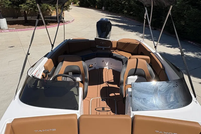 Slide: The Image of 2027 Tahoe 210 S boat interior with tan and black seating, parked outdoors. - 18