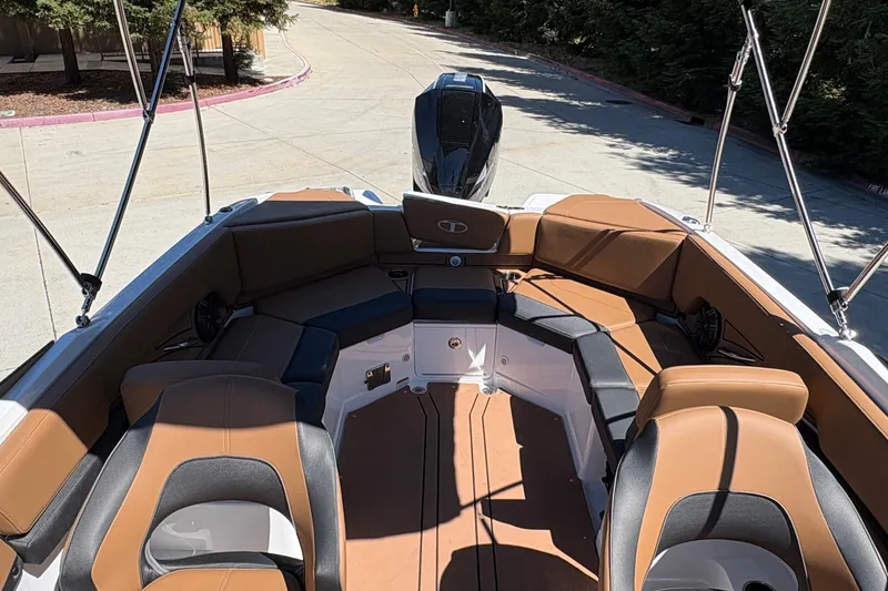 Slide: The Image of 2027 Tahoe 210 S boat interior with brown and black seating, docked outdoors. - 17