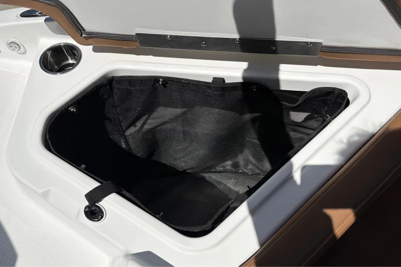 Slide: The Image of Open storage compartment in 2027 Tahoe 210 S boat, featuring black interior and cup holder. - 50