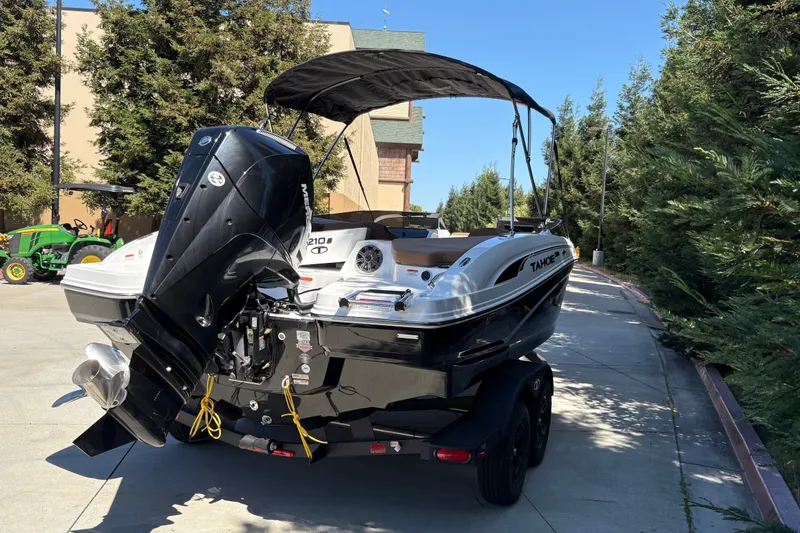 Slide: The Image of 2027 Tahoe 210 S boat with outboard motor on trailer, parked outdoors. - 12