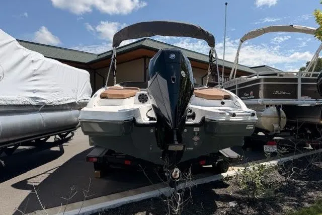 Slide: The Image of 2027 Tahoe 210 S boat with outboard motor, parked outdoors under a clear sky. - 2