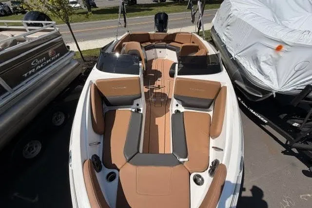Slide: The Image of 2027 Tahoe 210 S boat with tan seating and sleek design, docked outdoors. - 5