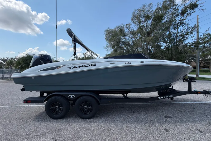 The Image of 2027 Tahoe 210 S boat on trailer, parked outdoors under a partly cloudy sky. - 0
