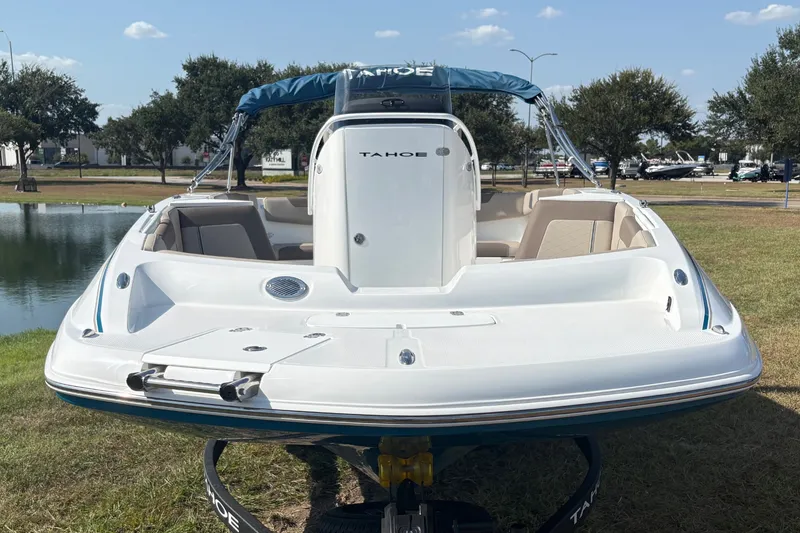 Slide: The Image of A white 2027 Tahoe 2150 CC boat on a trailer beside a pond. - 2