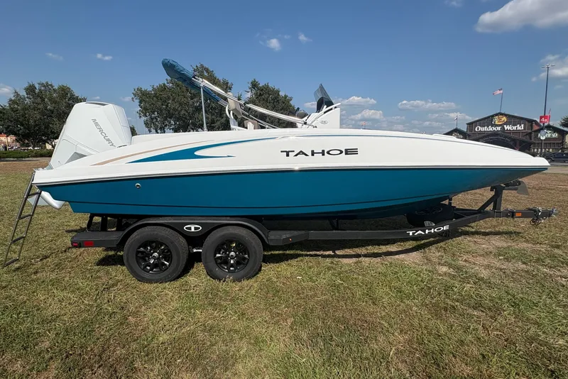 Slide: The Image of A blue and white 2027 Tahoe 2150 CC boat sits on a trailer in a grassy area. - 6