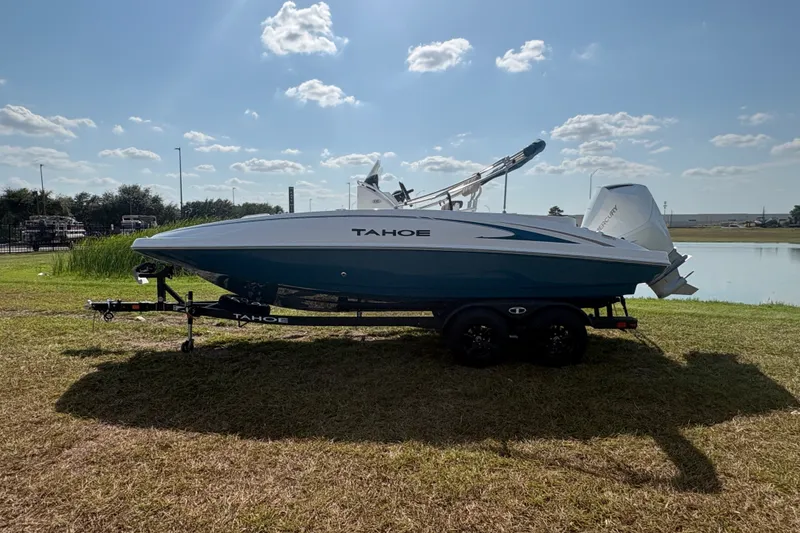 Slide: The Image of 2027 Tahoe 2150 CC boat on trailer by a lake under a clear sky. - 1