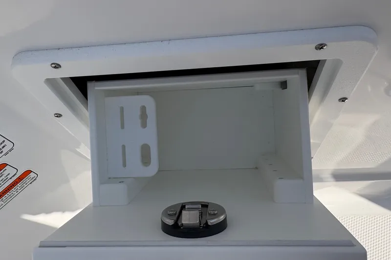 Slide: The Image of Open storage compartment on 2027 Tahoe 2150 CC boat, featuring a secure latch mechanism. - 13
