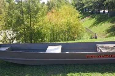 The Image of 2027 Tracker Grizzly 14 Jon boat on grassy area near trees. - 0