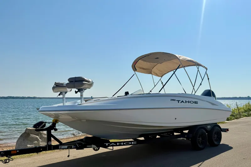 The Image of 2027 Tahoe 2150 boat on trailer by the lake under clear blue sky. - 1