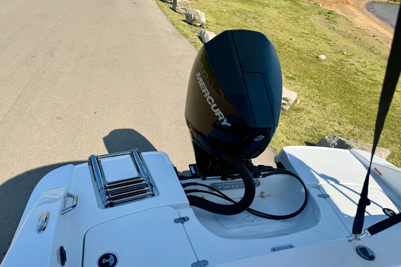 Slide: The Image of 2027 Tahoe 2150 boat with Mercury outboard motor, parked on a sunny lakeside road. - 19