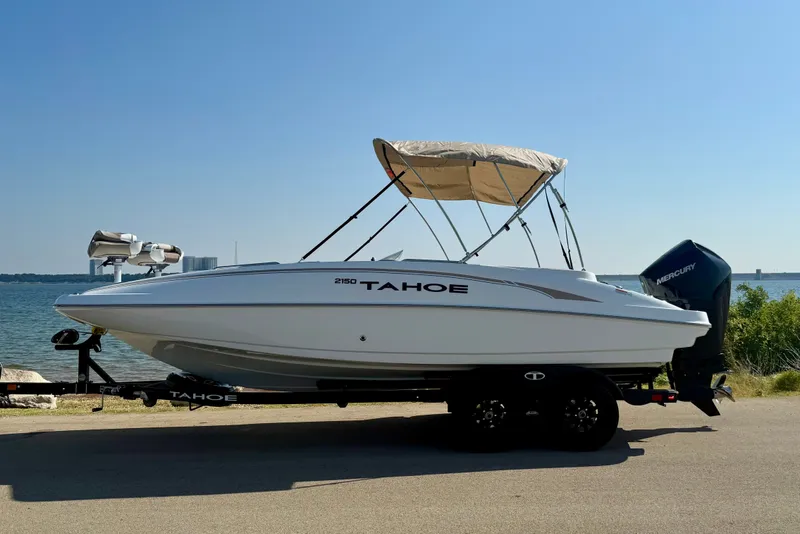 Slide: The Image of 2027 Tahoe 2150 boat on trailer by the water, featuring a Mercury outboard motor. - 22