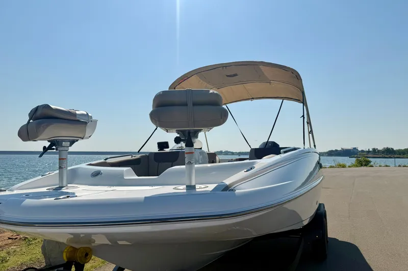Slide: The Image of 2027 Tahoe 2150 boat with canopy, parked by a serene lakeside under clear blue skies. - 17