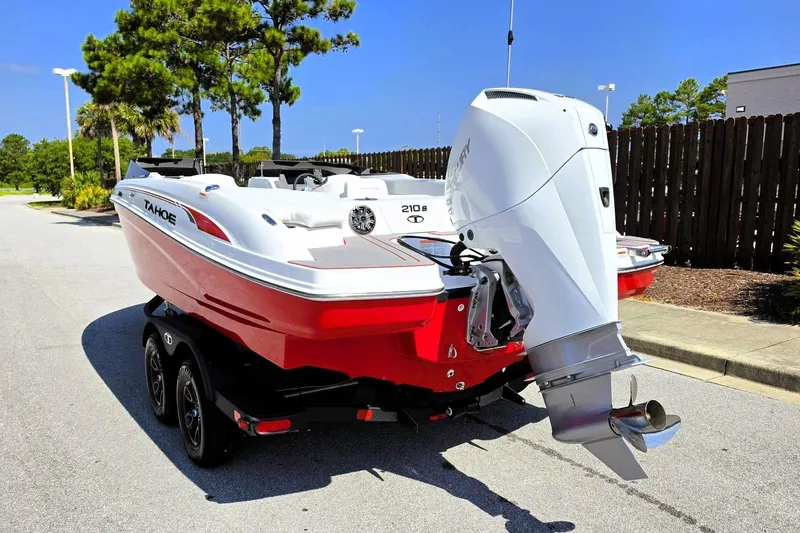 Slide: The Image of Red 2027 Tahoe 210 S boat with outboard motor on a trailer, parked outdoors. - 13