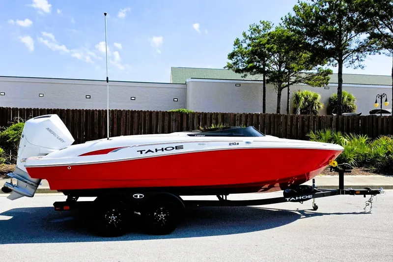 The Image of Red 2027 Tahoe 210 S boat on trailer, parked outdoors under clear sky. - 0