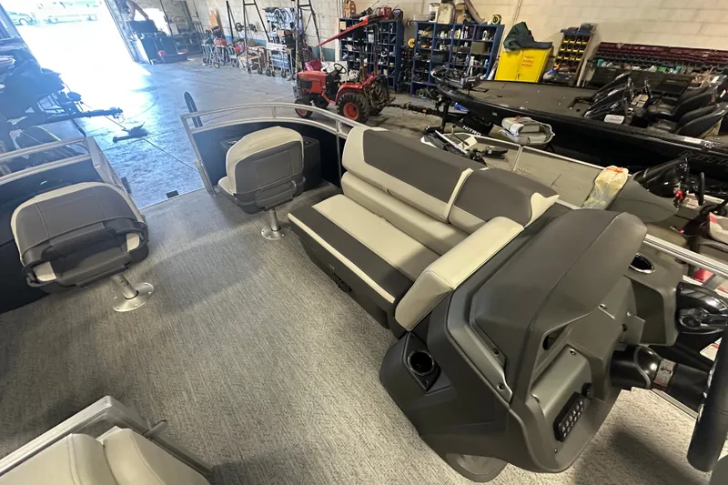 Slide: The Image of 2027 Sun Tracker Fishin' Barge 20 DLX interior with seating and steering console in a workshop. - 14