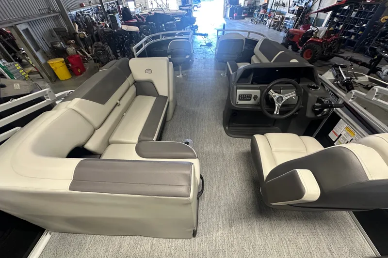 Slide: The Image of 2027 Sun Tracker Fishin' Barge 20 DLX interior with seating and steering console in a showroom. - 13