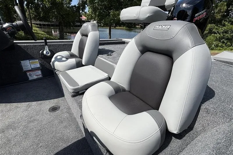 Slide: The Image of 2027 Tracker Pro Team 195 boat seats, featuring gray and black upholstery, near a serene lake. - 19