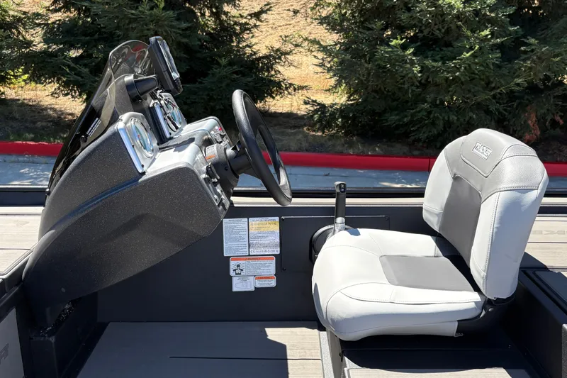 Slide: The Image of 2027 Tracker Pro 170 boat interior with steering wheel and seat, surrounded by trees. - 25