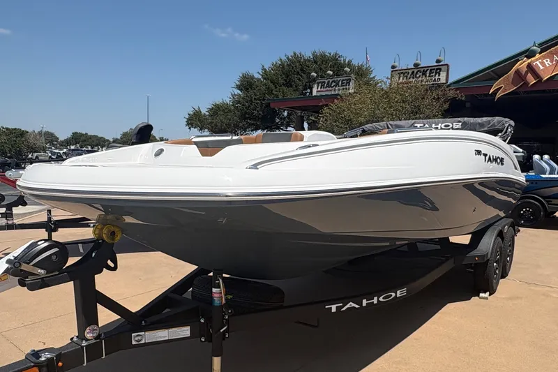 The Image of A white 2027 Tahoe 2150 boat on a trailer in a showroom setting. - 0