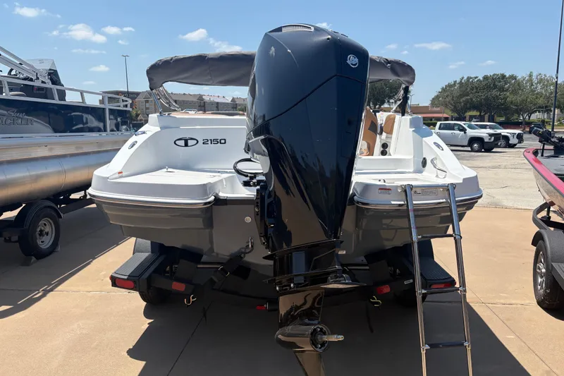Slide: The Image of 2027 Tahoe 2150 boat with outboard motor and ladder, parked on a sunny day. - 105