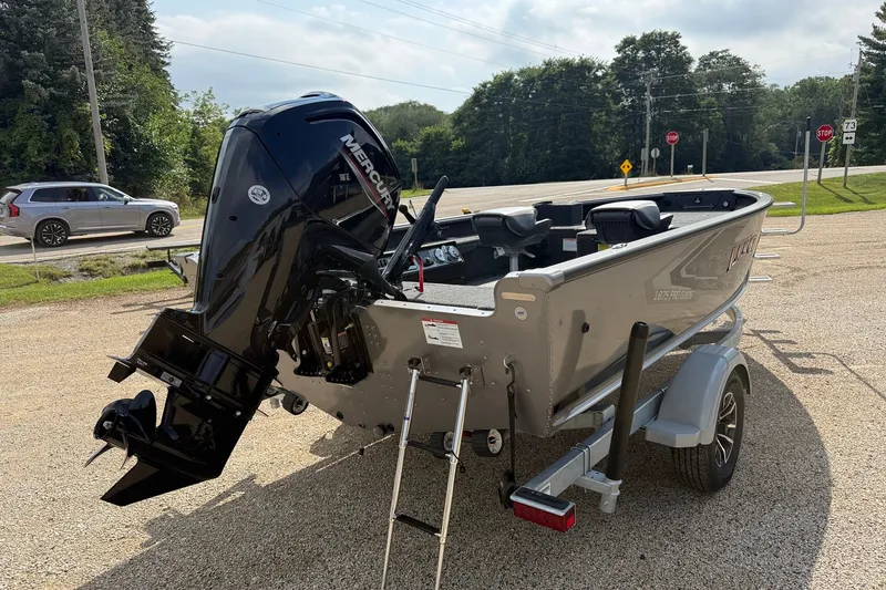 Slide: The Image of 2027 Lund 1875 Pro Guide boat on trailer with Mercury outboard motor, parked outdoors. - 3