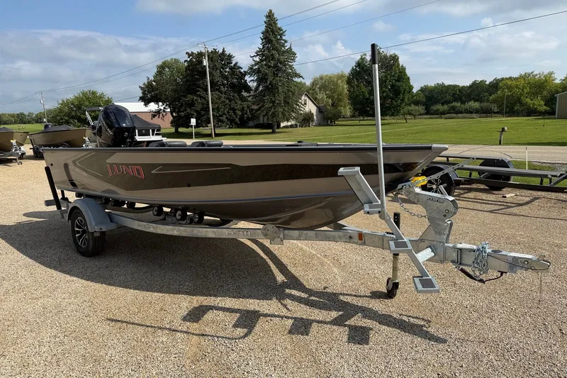 Slide: The Image of 2027 Lund 1875 Pro Guide boat on trailer, parked outdoors on gravel. - 2