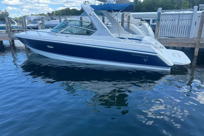 Slide: The Image of 2004 Formula 280 Sun Sport boat docked on calm water under a blue sky. - 2