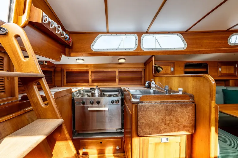 Slide: The Image of Interior of 1987 Hinckley Sou'wester 42 sailboat, featuring a wooden galley with stove and sink. - 27