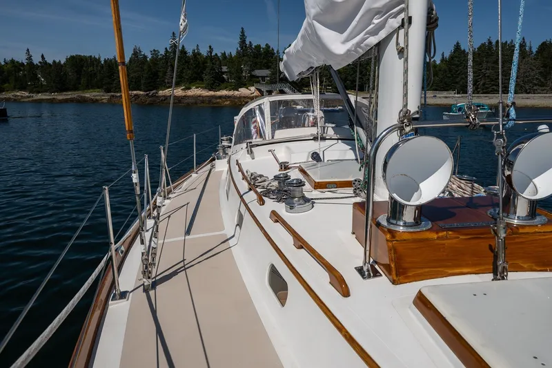 Slide: The Image of Hinckley Sou'wester 42 sailboat deck, 1987 model, docked near a forested shoreline. - 12