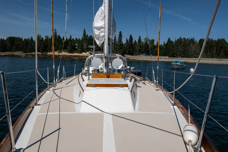 Slide: The Image of 1987 Hinckley Sou'wester 42 sailboat on calm water, surrounded by lush trees. - 10