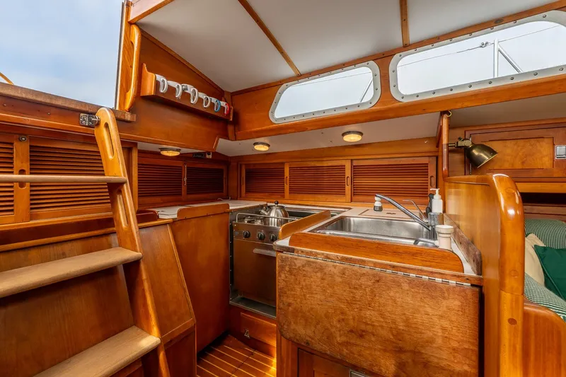 Slide: The Image of Interior of 1987 Hinckley Sou'wester 42 sailboat, featuring a wooden galley with sink and storage. - 28