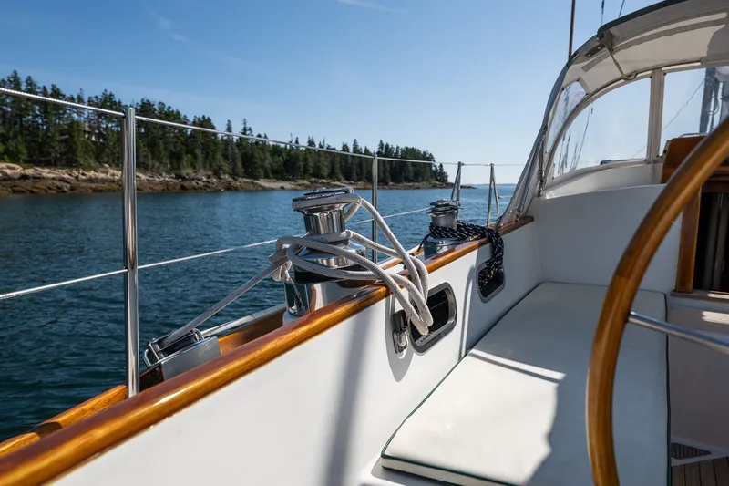 Slide: The Image of Hinckley Sou'wester 42 sailboat deck, 1987 model, cruising on a serene lake with forested shoreline. - 21