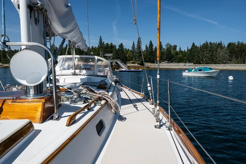 Slide: The Image of 1987 Hinckley Sou'wester 42 sailboat on calm water, with scenic forested shoreline. - 14