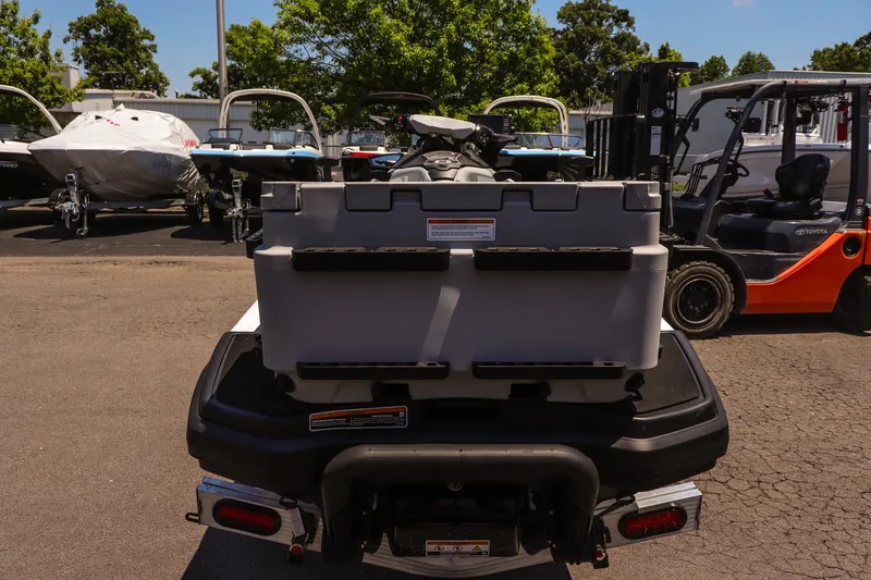 Slide: The Image of 2026 Sea-Doo FishPro Sport 170 with storage box, parked outdoors near boats and forklift. - 4