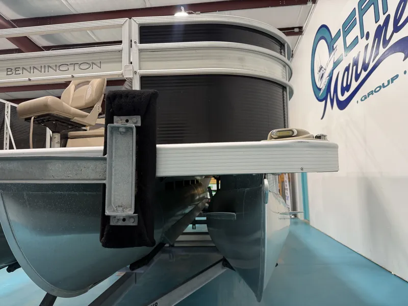 Slide: The Image of A 2020 Bennington pontoon boat is indoors. It features a black hull and beige seating. - 23
