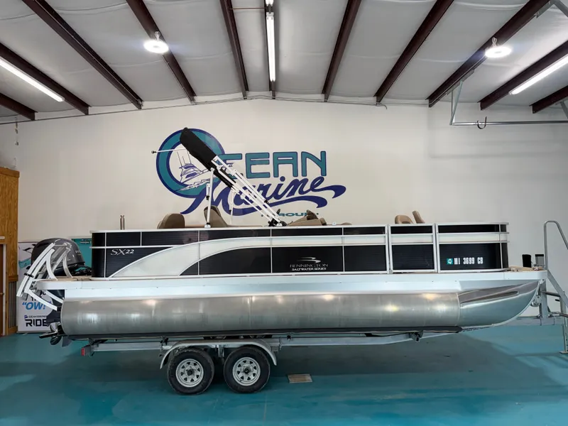 The Image of A 2020 Bennington pontoon boat on a trailer in a warehouse with a blue floor. - 1