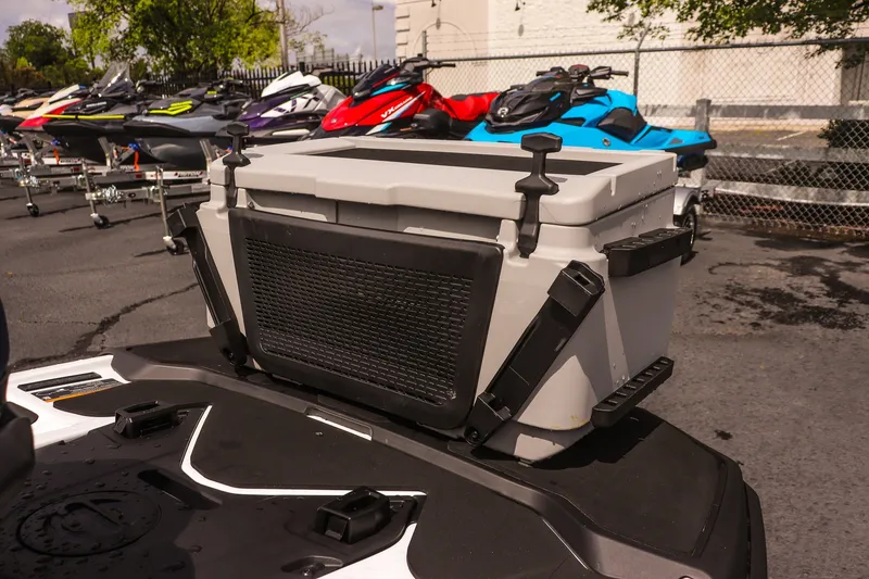 Slide: The Image of 2026 Sea-Doo FishPro Sport 170 with cooler, parked among other jet skis. - 9