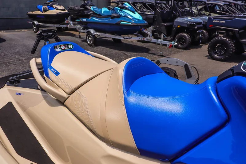 Slide: The Image of 2026 Sea-Doo Wake Pro 230 jet ski with blue and beige seating, parked outdoors. - 9
