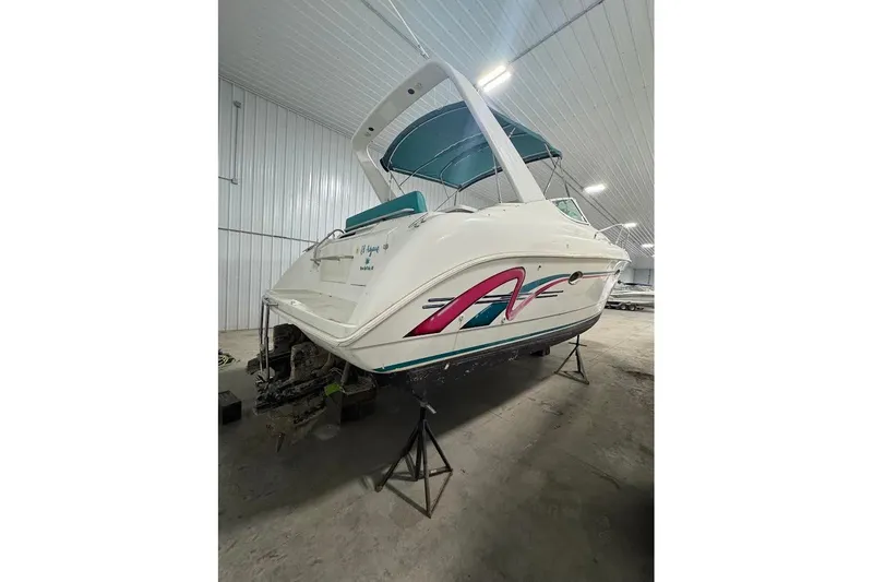 The Image of 1994 Silverton 310 Express boat in storage, featuring colorful graphics and teal canopy. - 1