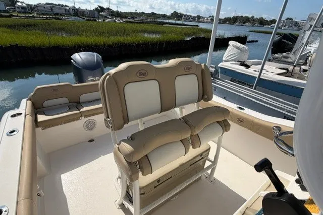 Slide: The Image of 2019 Key West 239 FS boat interior with seating and outboard motor, docked by marshland. - 17