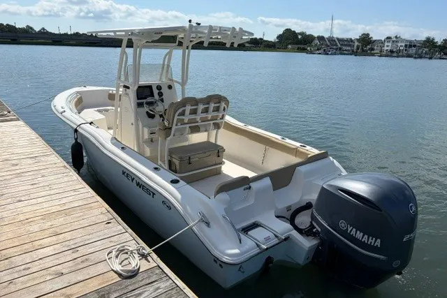 Slide: The Image of 2019 Key West 239 FS boat docked, featuring Yamaha outboard motor, calm water backdrop. - 2