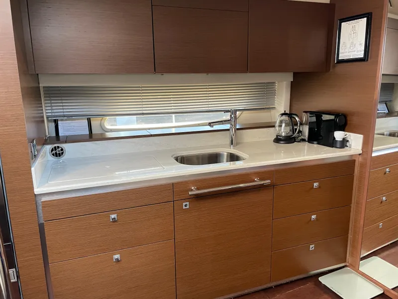 Slide: The Image of The 2012 Sea Ray 470 Sundancer's galley features wooden cabinets, a sink, and a coffee maker. - 30