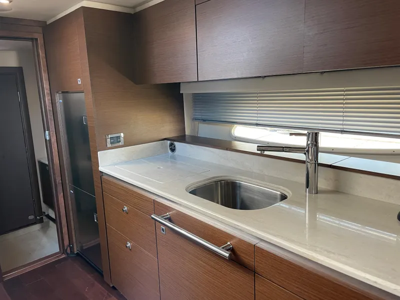 Slide: The Image of The 2012 Sea Ray 470 Sundancer's kitchen features a modern sink and wooden cabinetry. - 31