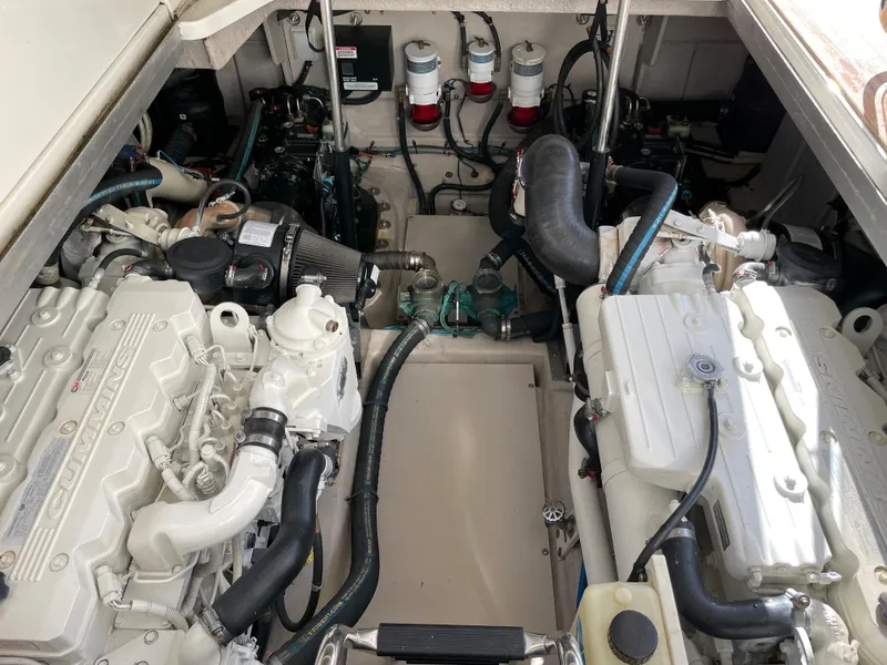 Slide: The Image of Engine room of the 2012 Sea Ray 470 Sundancer with two large engines and various hoses. - 48