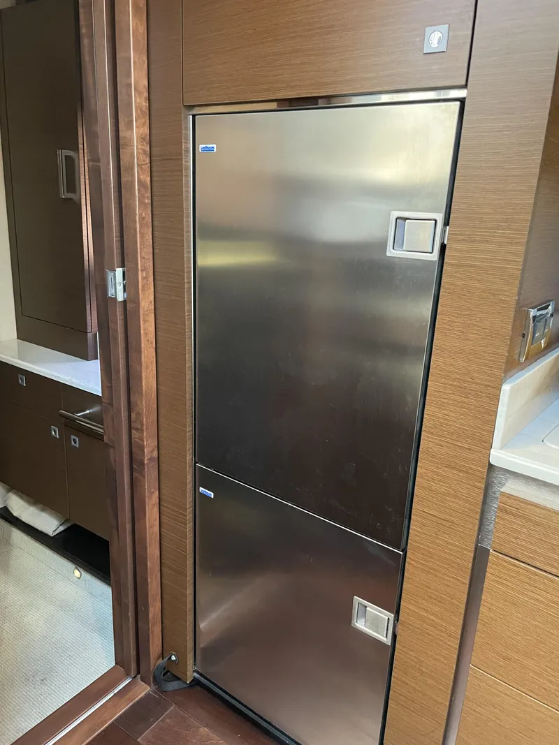 Slide: The Image of A sleek stainless steel refrigerator in a modern boat kitchen with wood paneling. - 32