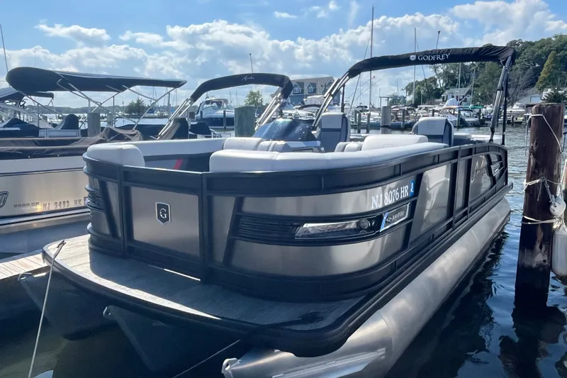 Slide: The Image of 2022 Godfrey AquaPatio 235 ULC pontoon boat docked at marina under blue sky. - 2