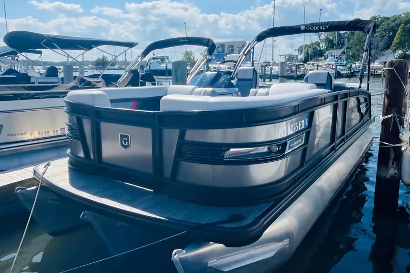 The Image of 2022 Godfrey AquaPatio 235 ULC pontoon boat docked at marina under blue sky. - 0