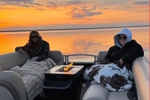 Slide: The Image of Two people relaxing on a 2022 Godfrey AquaPatio 235 ULC boat at sunset. - 20